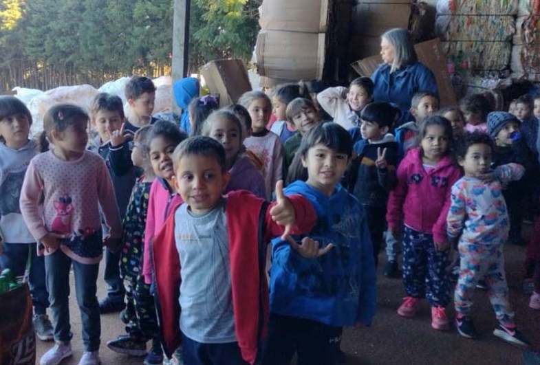 Crianças reunidas aprendem sobre o destino do lixo e a importância da reciclagem após a visita ao aterro