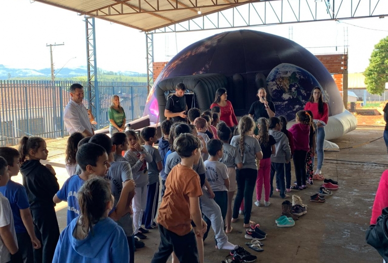 Crianças animadas aguardam na fila  ara entrar no planetário móvel