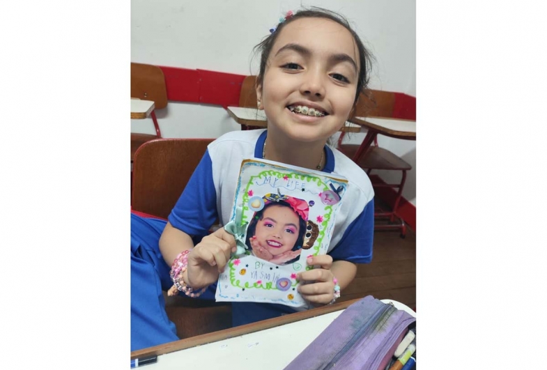 Yasmin segurando  seu primeiro livro  escrito em inglês